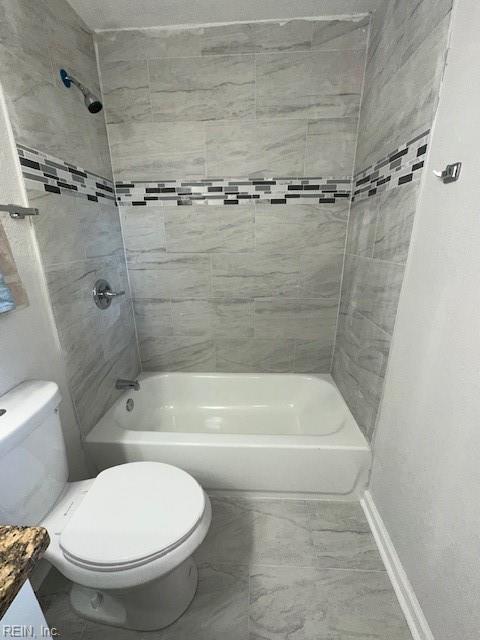 bathroom featuring shower / washtub combination, toilet, and baseboards