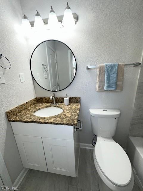 full bath featuring vanity, toilet, a bathtub, and baseboards