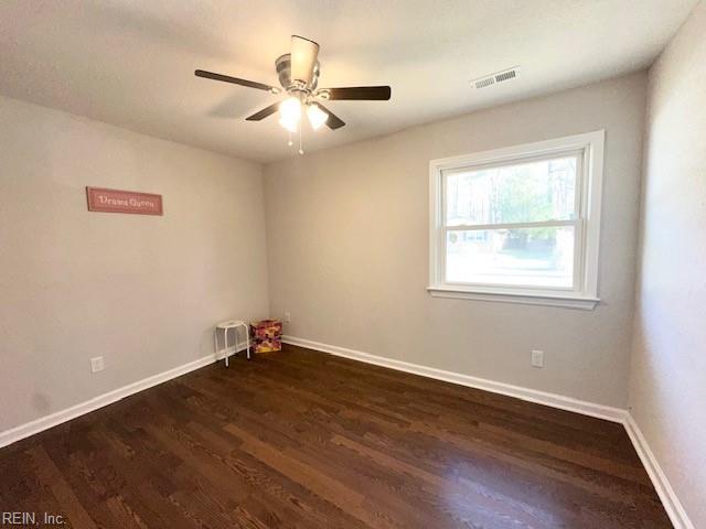 unfurnished room with ceiling fan, wood finished floors, visible vents, and baseboards