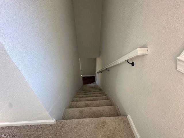 staircase featuring baseboards and a textured wall