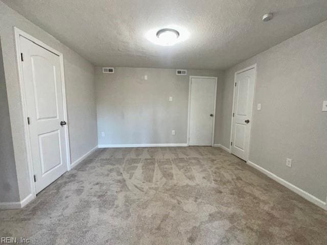 carpeted spare room featuring baseboards, visible vents, and a textured ceiling