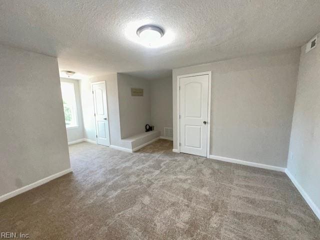 spare room with visible vents, carpet, baseboards, and a textured ceiling