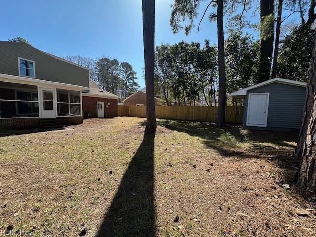 view of yard with an outbuilding, a sunroom, a storage shed, and fence