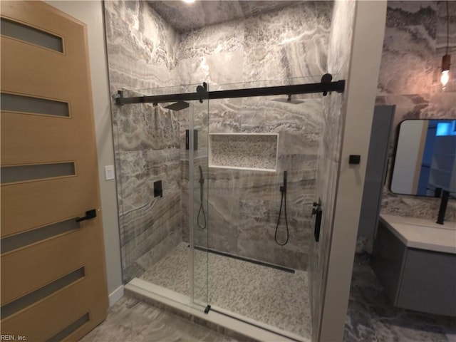 bathroom with a marble finish shower and vanity