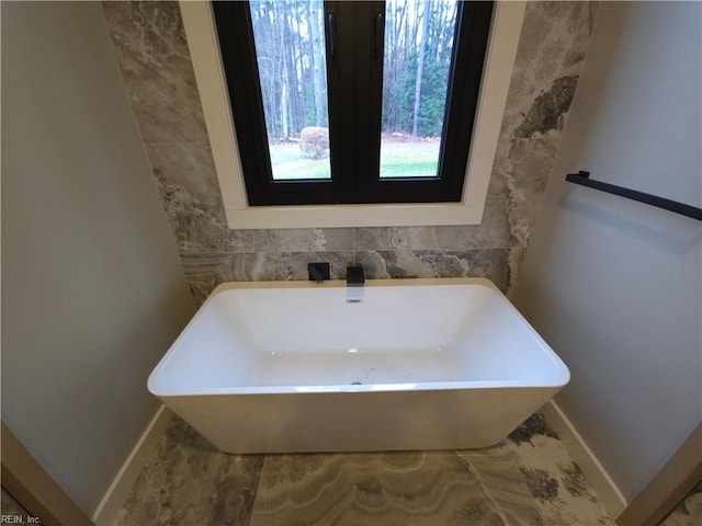 full bathroom featuring a soaking tub and baseboards