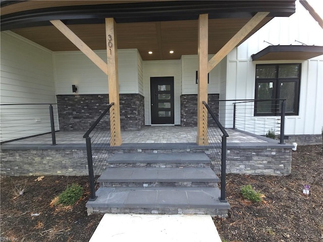 view of exterior entry with covered porch and board and batten siding