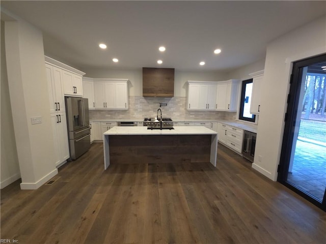 kitchen featuring white cabinets, wall chimney exhaust hood, high quality fridge, and a sink