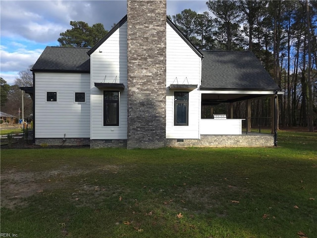 back of property with crawl space, a yard, a chimney, and a shingled roof