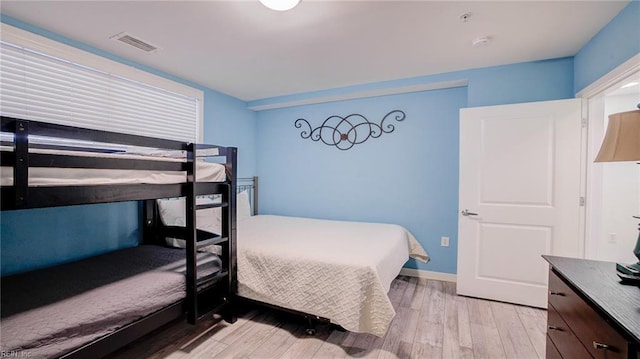 bedroom with visible vents, light wood-type flooring, and baseboards