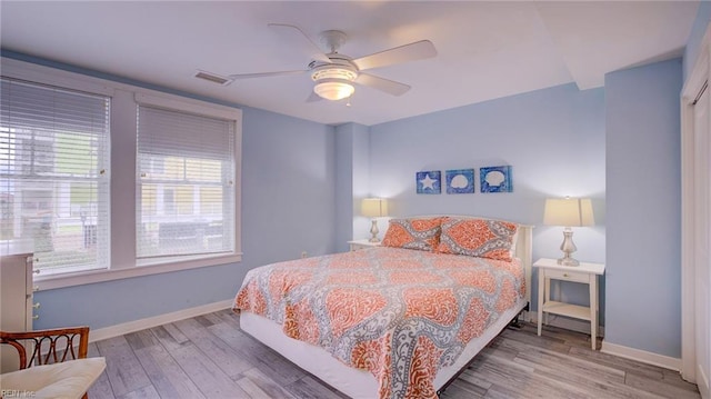 bedroom featuring visible vents, baseboards, wood finished floors, and a ceiling fan