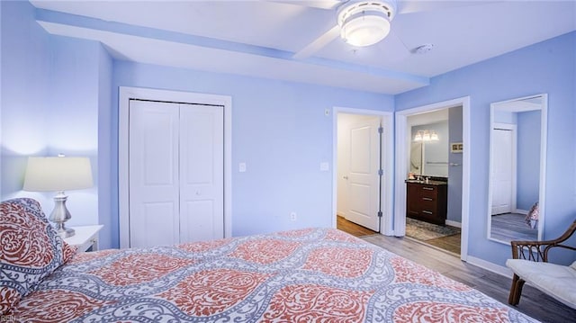 bedroom featuring baseboards, ensuite bathroom, wood finished floors, a closet, and a ceiling fan