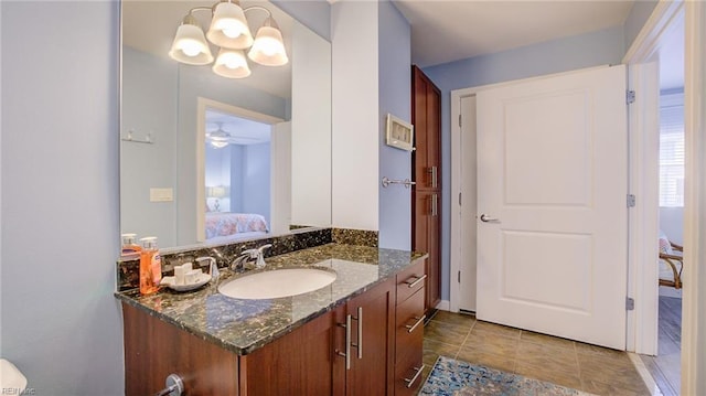 ensuite bathroom featuring vanity, ensuite bath, ceiling fan with notable chandelier, and tile patterned flooring