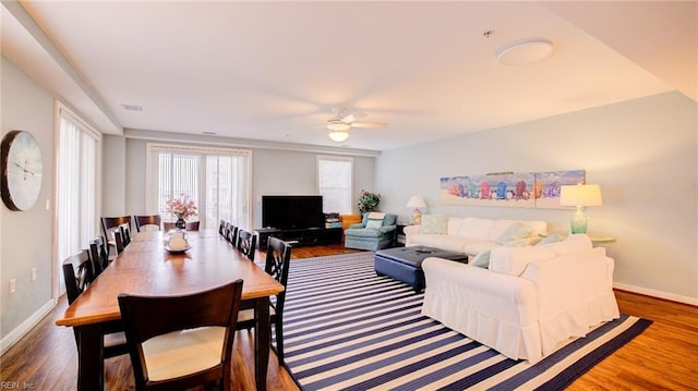 living room with ceiling fan, visible vents, baseboards, and wood finished floors