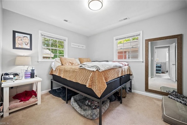 bedroom featuring visible vents, light colored carpet, and multiple windows