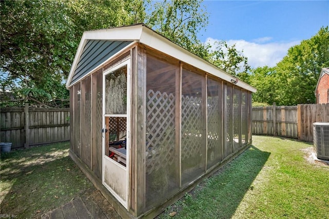 view of outdoor structure with an outdoor structure, a fenced backyard, and central AC