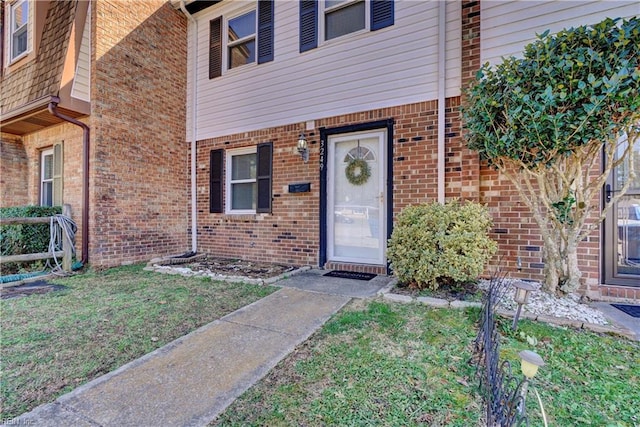 property entrance with brick siding and a lawn