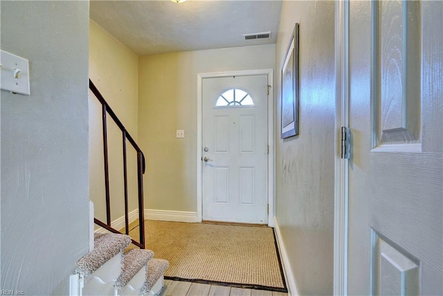 foyer entrance featuring visible vents, baseboards, and stairway