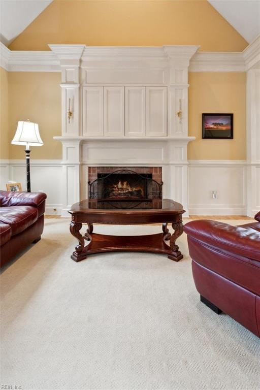 living room featuring vaulted ceiling, a brick fireplace, a wainscoted wall, and carpet floors