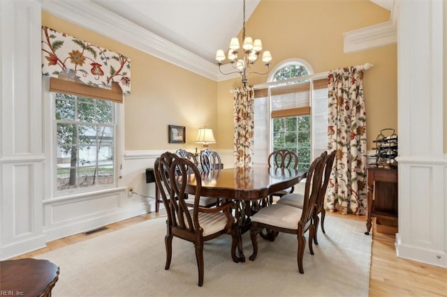 dining area with visible vents, wood finished floors, wainscoting, crown molding, and a chandelier