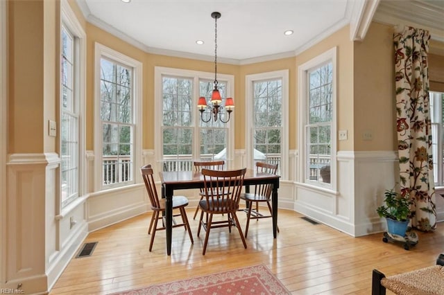 dining space with light wood finished floors, visible vents, and crown molding