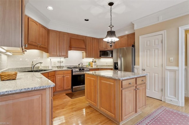 kitchen featuring a sink, light stone counters, appliances with stainless steel finishes, and custom range hood