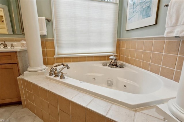 bathroom with tile patterned floors, a tub with jets, vanity, and ornate columns