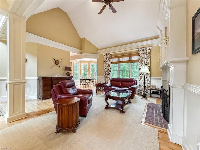 living room with a decorative wall, wood finished floors, wainscoting, and ornate columns