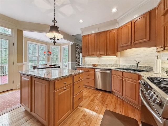 kitchen featuring a center island, light stone countertops, light wood-type flooring, stainless steel appliances, and a sink