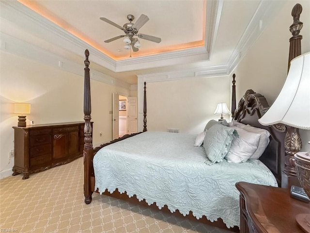 bedroom featuring light carpet, visible vents, crown molding, and a tray ceiling