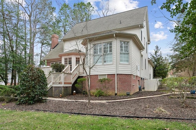 rear view of house with a wooden deck, brick siding, and a chimney