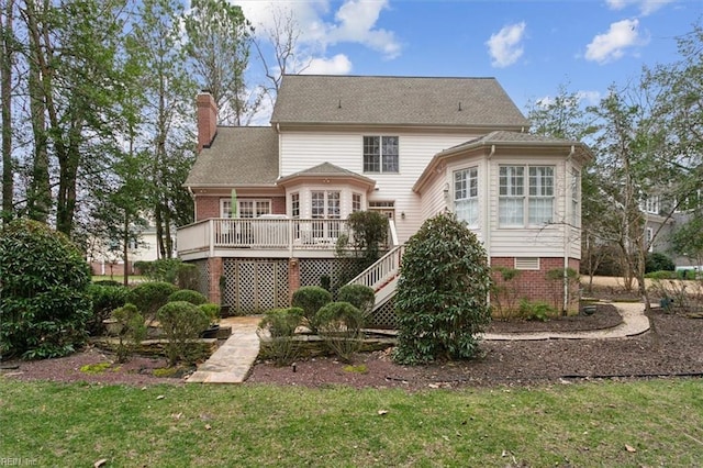 back of house featuring a chimney, a lawn, a wooden deck, and stairs