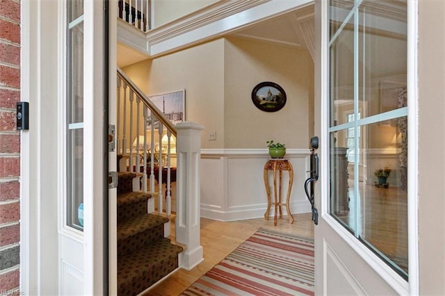 interior space featuring stairway, a decorative wall, wood finished floors, and a wainscoted wall