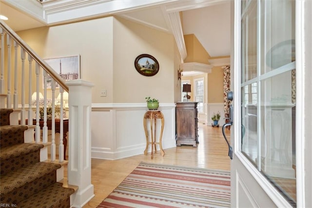 entrance foyer with a wainscoted wall, light wood-style flooring, and a decorative wall