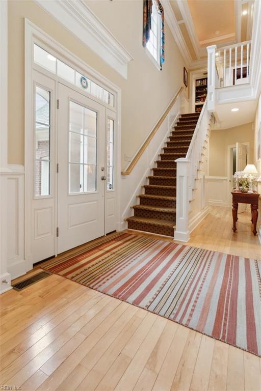 foyer entrance featuring visible vents, crown molding, a high ceiling, and hardwood / wood-style floors