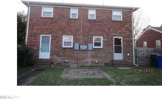 rear view of property with entry steps, a yard, fence, and brick siding