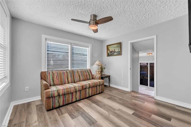 living room with a wealth of natural light, baseboards, and wood finished floors