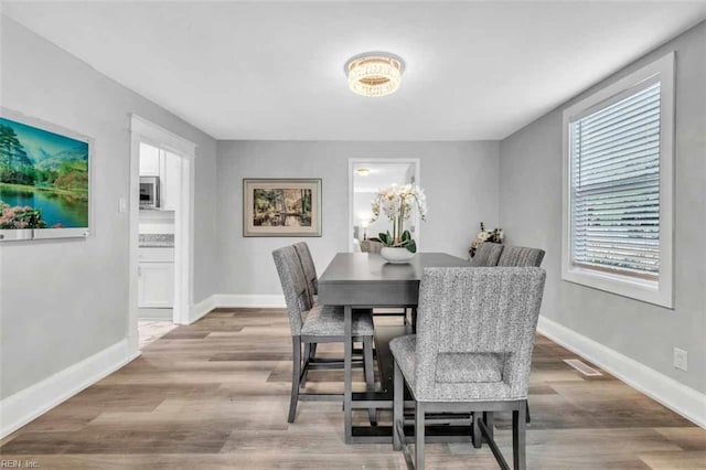 dining space with visible vents, baseboards, and wood finished floors