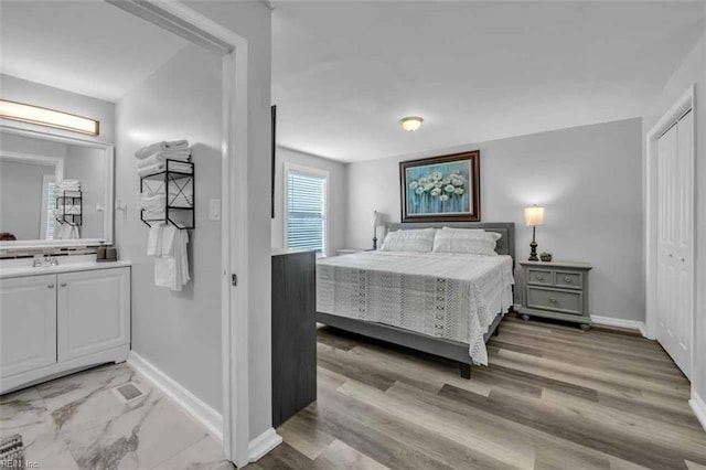 bedroom with a closet, baseboards, and light wood finished floors