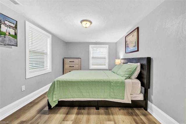 bedroom with visible vents, baseboards, and wood finished floors