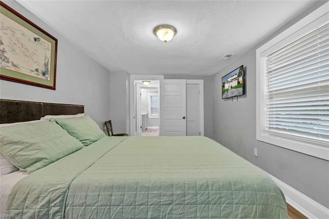 bedroom featuring visible vents, baseboards, and ensuite bath