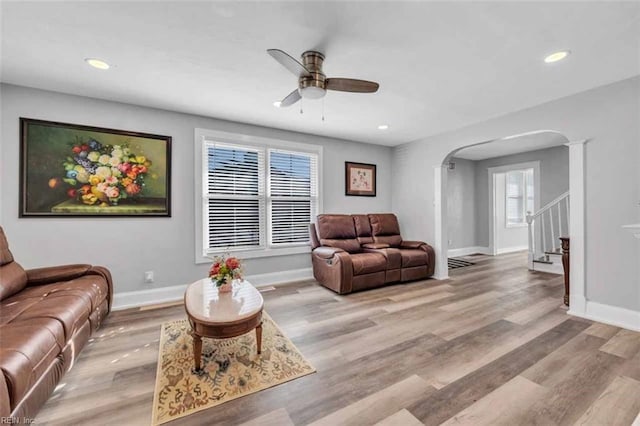 living area featuring recessed lighting, light wood-type flooring, arched walkways, and baseboards