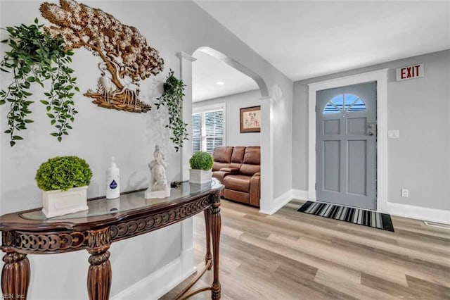 entryway with baseboards, arched walkways, visible vents, and light wood-style flooring