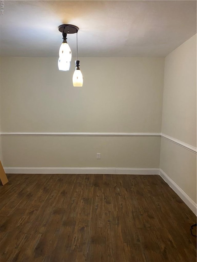 spare room featuring dark wood-type flooring and baseboards