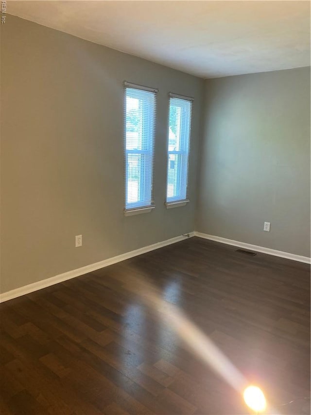 spare room with dark wood-style floors and baseboards