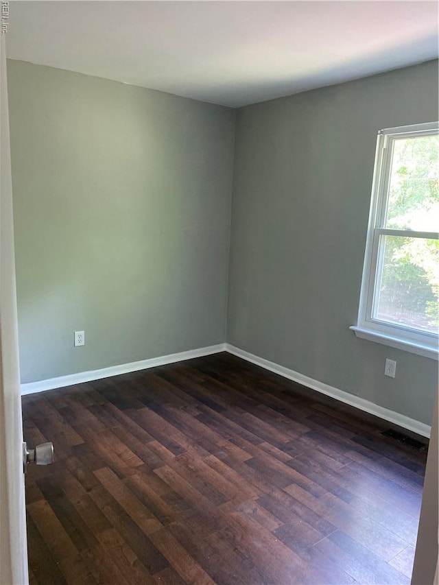 unfurnished room with dark wood finished floors and baseboards