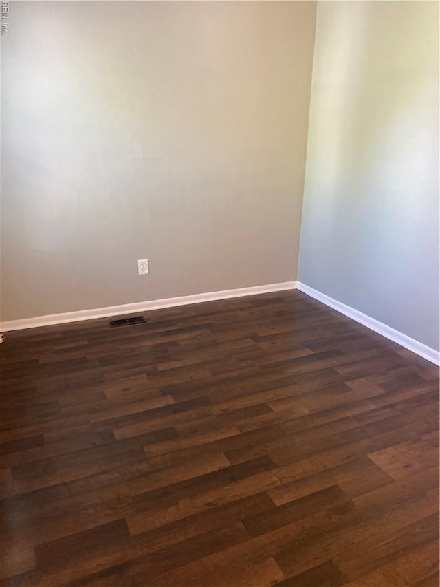 spare room featuring baseboards and dark wood finished floors