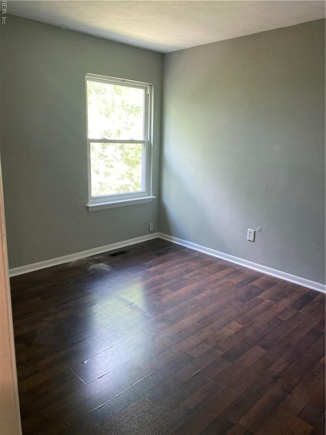 spare room featuring dark wood-type flooring and baseboards