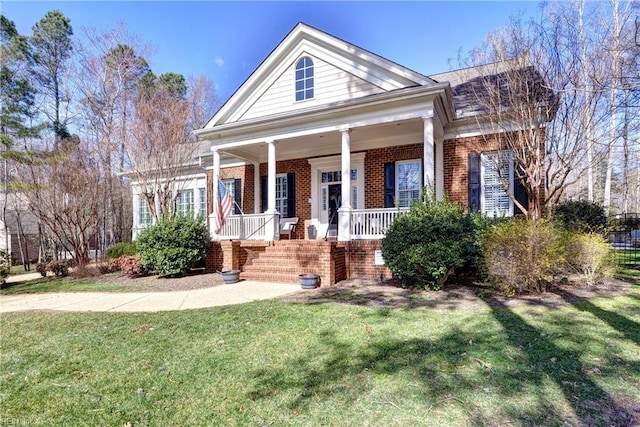 neoclassical home featuring brick siding, a porch, and a front lawn