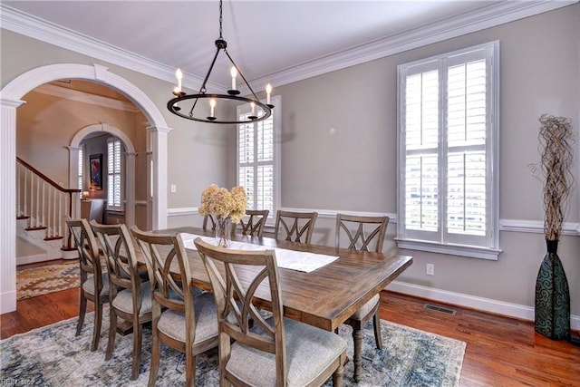 dining space featuring visible vents, arched walkways, plenty of natural light, and wood finished floors