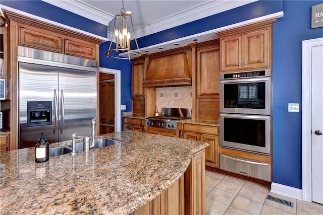 kitchen featuring decorative backsplash, brown cabinets, custom exhaust hood, stainless steel appliances, and a warming drawer